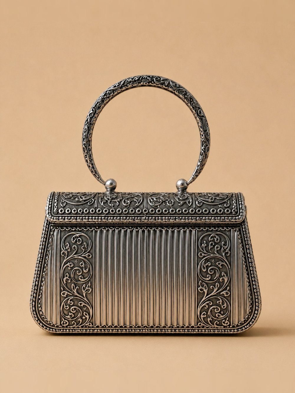 Chandrika Royale oxidized silver clutch with floral scrollwork and fluted side panels, shown against a plain background