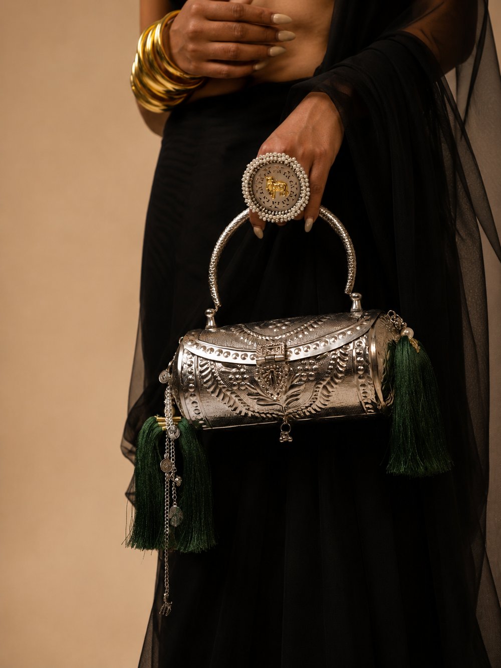 Emerald Heirloom clutch held by hand, showing the faux-pearl clasp and hanging tassels