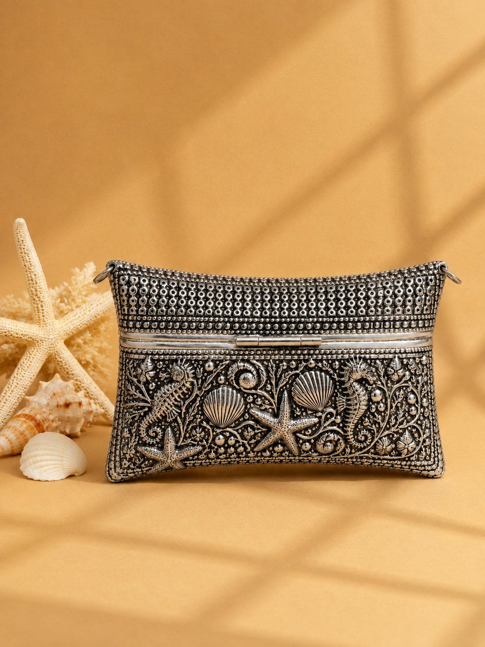 Ocean Majesty clutch showing seahorse and starfish engraving, styled with a starfish and coral