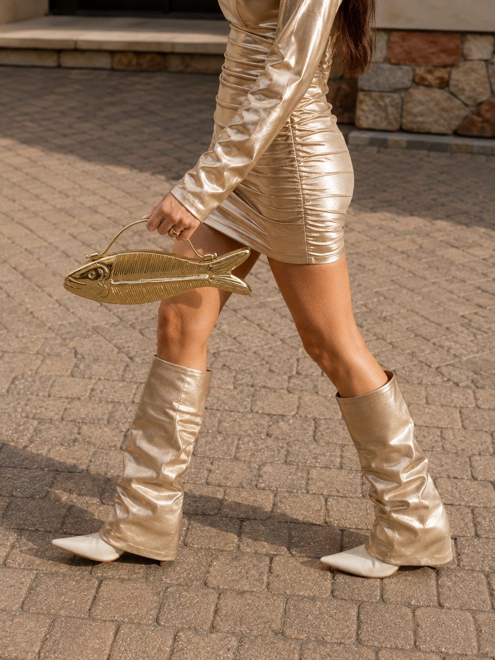 Ruby Koi clutch carried by hand, styled with a metallic gold dress and boots